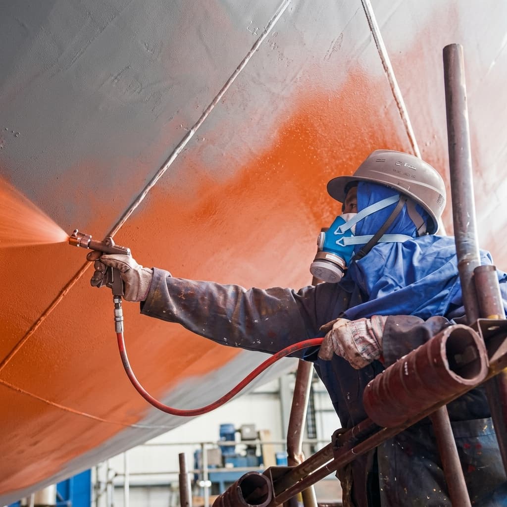 Applicator spraying Hempel's Globic 9000 antifouling onto a ship hull